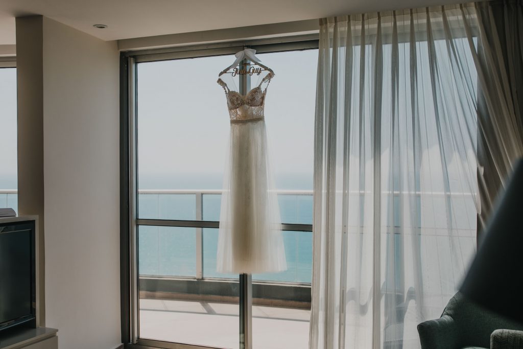 התארגנות לחתונה במלון, עם שמלה על החלון על רקע הים
